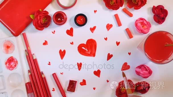 红色的调色板。在纸上画了许多的心。上面的艺术家桌子。情人节或母亲节概念