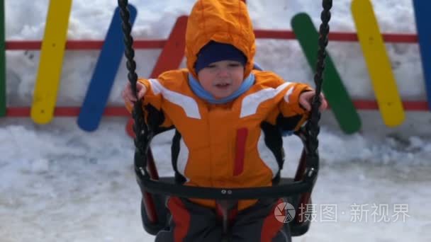 小男孩骑在冬天在秋千上视频