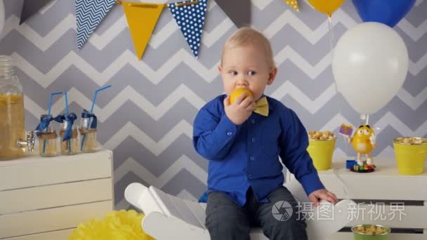 英俊的 1 岁的男孩，吃橙子