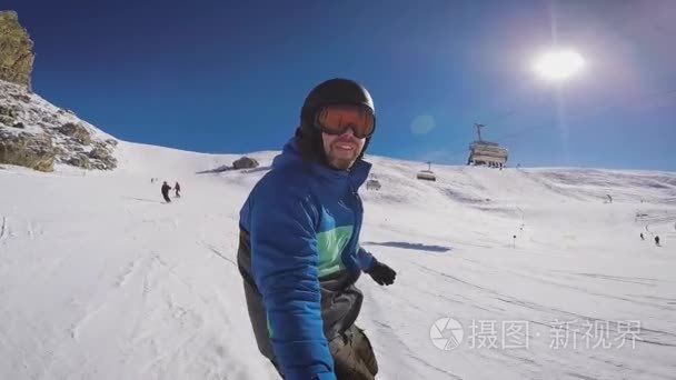 在冬季在阿尔卑斯山滑雪。一个人滚动在滑雪板上的山庄雪覆盖的小径上。这个家伙把自己起飞极端的相机上