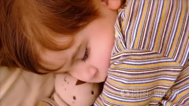 3 岁的小男孩睡在一起的泰迪熊的画像。他母亲的手抚摸他