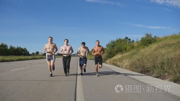 在公路慢跑跑步男子组。男性的运动健儿们在夏天训练户外。强肌的年轻人一起在锻炼期间在农村公路上行使。积极的生活方式。慢动作