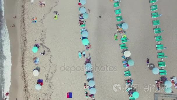 游客在海滩日光浴浴床与阳伞上休息