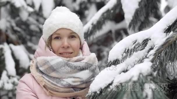 美丽的年轻女子在冬季森林，背景下的雪慢动作杉树的肖像