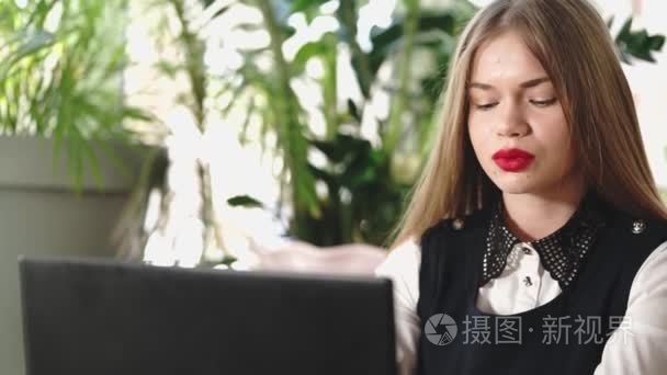 一个年轻的学生看起来她在社会网络中，坐在一家咖啡馆里的帐户通过视频