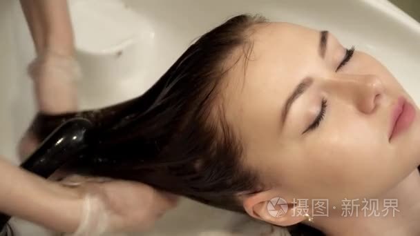发型师洗年轻女人头发特写视频