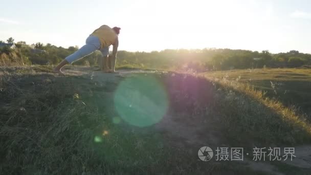 练瑜伽的白种人家伙移动，并在自然中的位置。运动的年轻人站在室外的瑜伽姿势。平衡的运动员。作为背景的美丽景观。健康积极的生活方式