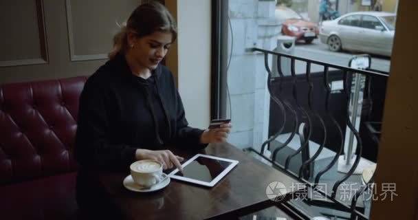 美丽的女人网上银行使用 ipad 与信用卡在线购物。在红色电影镜头拍摄。4 k