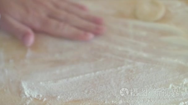 女手把面团擀圆用擀面杖的形式在桌子上，对厨师做饺子特写