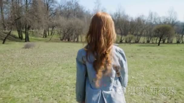 红头发的女孩在一个阳光明媚的公园玩