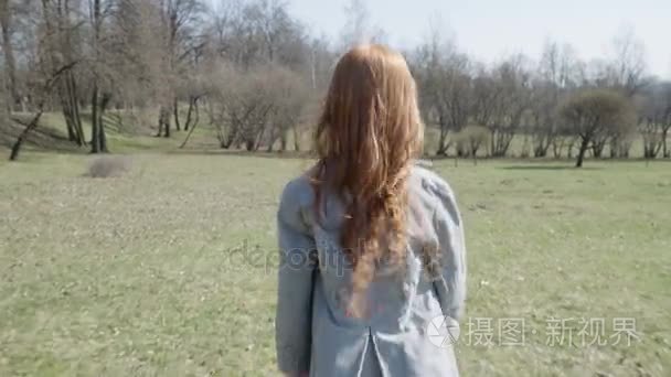 红头发的女孩在一个阳光明媚的公园玩