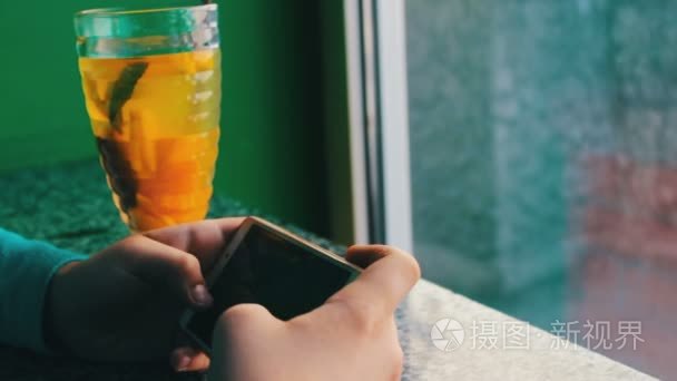一个男孩在旁肉桂柠檬奶茶咖啡厅里的智能手机上玩