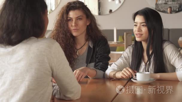 两个女孩聚精会神地听他们在咖啡馆里的朋友