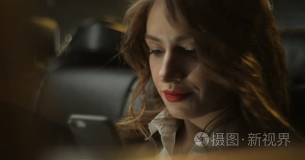 快乐有魅力的女人使用，通过车窗晚上手机上的发短信