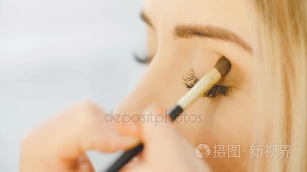 专业眼化妆师应用眼影粉。美丽的女人的脸。完美的化妆。美容时尚。睫毛。关闭和慢动作