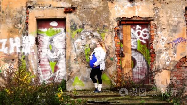 怀孕的女孩正站在一栋废弃建筑的门廊的坡道上视频