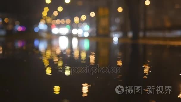 慢动作灯景圈反映水在夜间城市街道与小雨滴