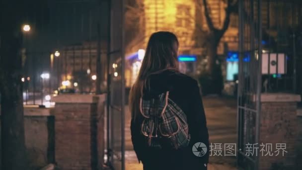 回来的年轻的黑发女人，走在夜晚的意大利罗马市中心的视图。女孩转身看到古罗马斗兽场