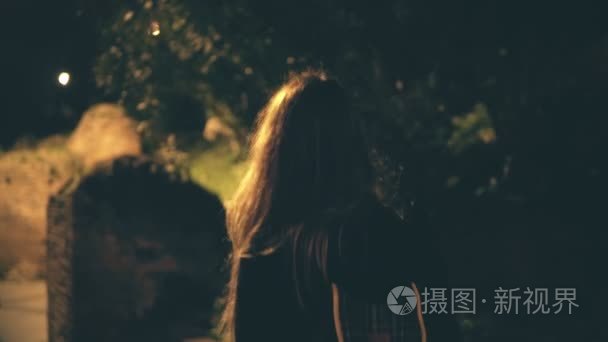 年轻的黑发女人晚一个人走夜路。女孩穿过市中心在罗马，意大利罗马斗兽场附近