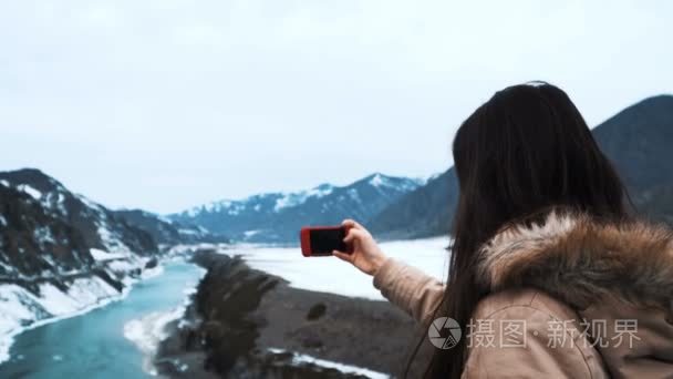 考虑自拍照背景的大山和绿色山区河流的白种人美女