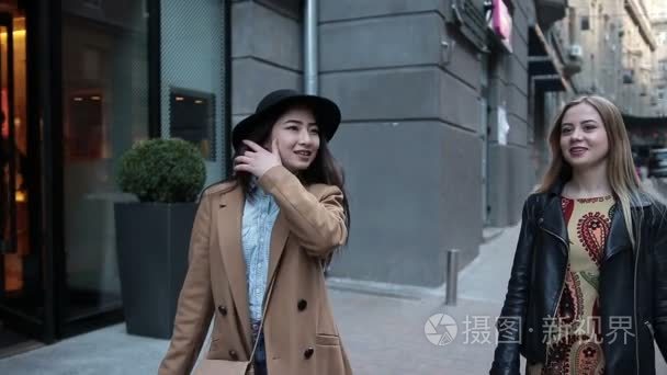 两个年轻女性的购物袋走在市