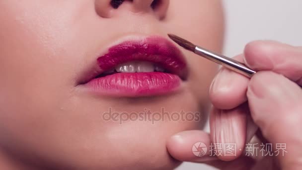 专业化妆师使嘴唇化妆的模型。美丽和时尚的概念。关闭