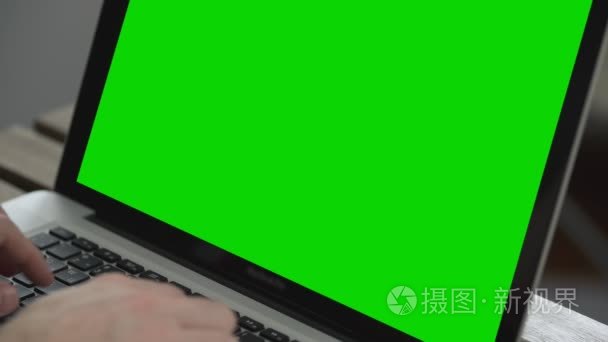 男人的手,在笔记本电脑键盘上打字工作.绿色屏幕关闭短视频