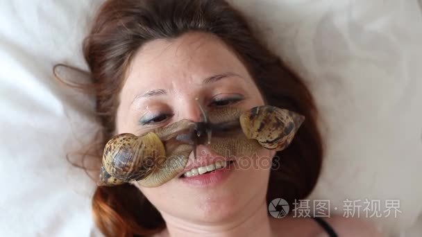 一个年轻女人在水疗中心接收与非洲蜗牛褐云的面部按摩。蜗牛吃死皮制作的。最后，它使皮肤光滑和新鲜视频