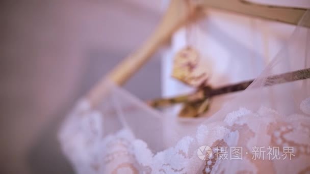 美丽的白色婚纱礼服挂在卧室里挂在衣架上。新娘的早上准备，详细的乡村风格