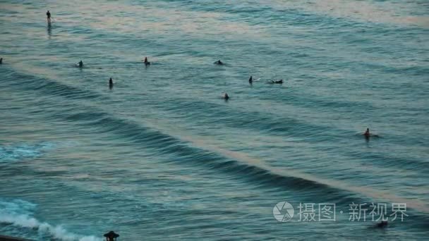 一群人在夏天的傍晚漂浮在海水中冲浪板视频