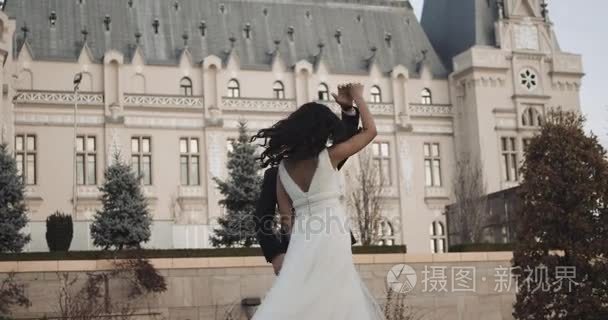 快乐的一对新婚夫妇，在城堡前一起跳舞。4 k