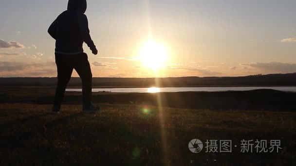 在夏天的草原上，夕阳的路人。在山顶上，年轻人的剪影