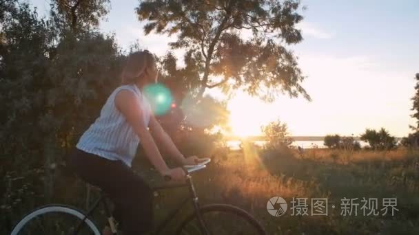 在日落时时髦女孩骑自行车视频