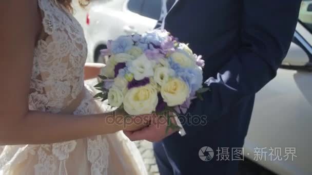 新娘和新郎抱着色彩缤纷的婚礼花束。婚姻观念。美丽年轻夫妇外性质。新婚夫妇与时尚的花束