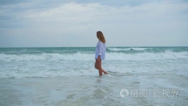 一个年轻的姑娘走在岸边的沙滩视频