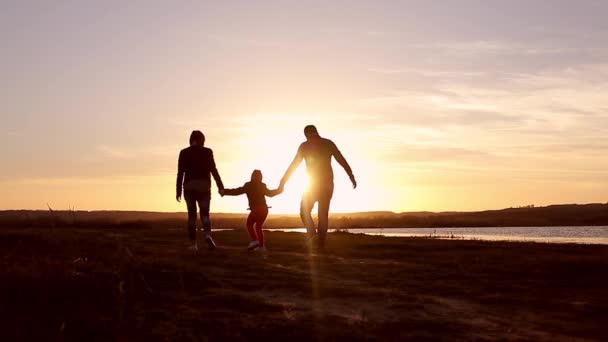 剪影,与母亲和父亲,在夕阳下,夏季家庭幸福的孩子.