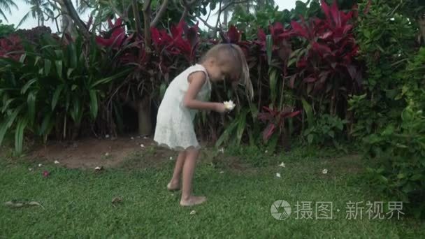 小女孩收集鸡蛋花在热带花园素材视频