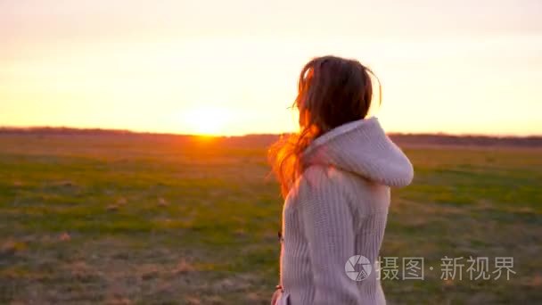 女人在日落时分广阔田野里跑