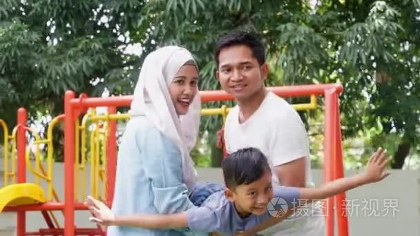 亚洲家庭摆动他们的儿子在公园视频