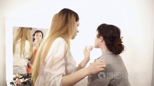 化妆师在年轻女人脸上应用基地视频