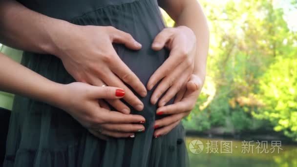 手抚着孕妇的肚子.丈夫手抚摸肚皮他怀孕的妻子.