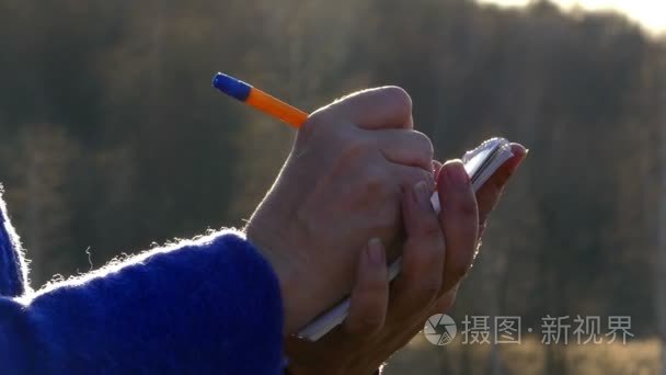 一个成年的女子写东西在记事本中，你可以看到她手里的笔和笔记本特写视频