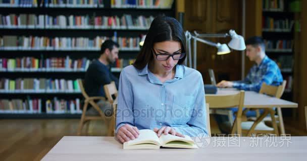 在库中拿着书，在做搜索以后学习和快乐的笑一个美丽的年轻女子的画像。理念︰ 教育、 画像，图书馆，和勤奋好学