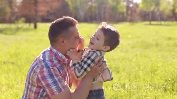 快乐的父亲亲吻他的小儿子在公园里
