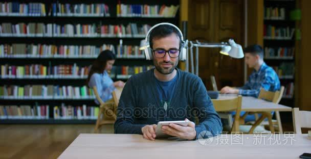 一群年轻的男人和女人在图书馆学习、 看书，或者听音乐的计算机上完全安静和放松。文化、 教育、 休闲和学习的概念