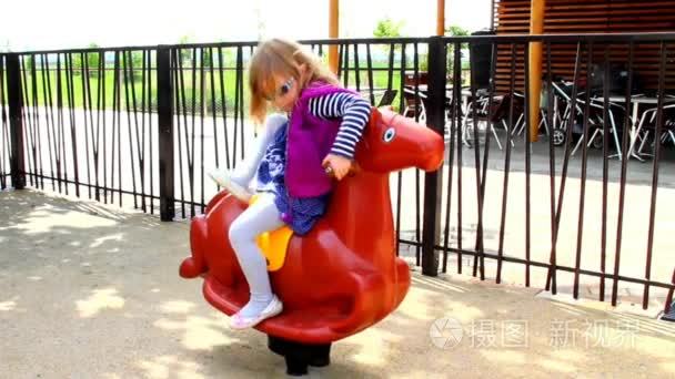 小女孩骑着木马在儿童游乐场视频
