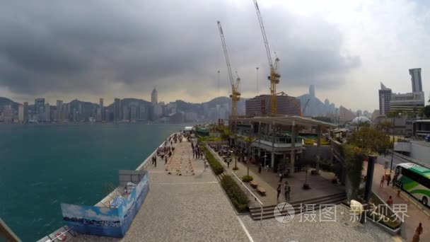 A number of people walking along Tsim Sha Tsui Promenade (time-l