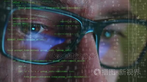 男性黑客网络攻击，但绿色黑客代码字符的二进制文件的计算机上工作反映在他的脸上