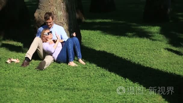 一个女孩在一个男人的大腿上.一对情侣在公园的一棵树下的草地上休息