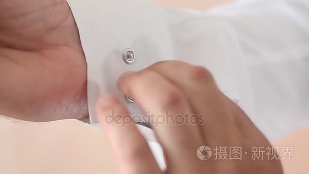 男子系按钮上的白衬衣的袖子，男人穿上一件白衬衫